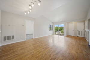 Unfurnished living room with light wood finished floors and vaulted ceiling