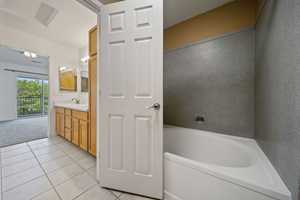 Bathroom featuring tile patterned flooring, vanity, and a tub