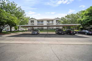 View of property featuring covered and uncovered parking