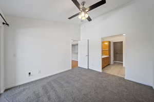 Unfurnished bedroom featuring light carpet, high vaulted ceiling, ensuite bathroom, a walk in closet, and light tile patterned floors