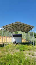 View of parking featuring a storage shed and a carport