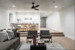 Living area with light carpet, ceiling fan, a textured ceiling, and recessed lighting