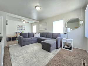 Carpeted living area with ceiling fan
