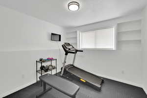 Exercise room with baseboards and a textured ceiling