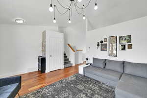 Living room featuring stairs, wood finished floors, and a chandelier