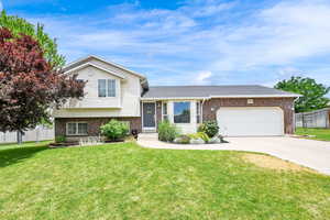 Tri-level home featuring brick siding, a garage, driveway, and roof with shingles