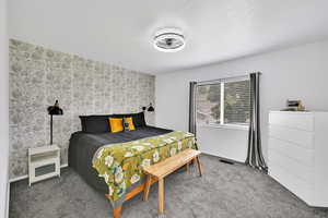 Bedroom with carpet floors, an accent wall, and wallpapered walls