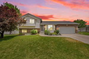 Tri-level home featuring brick siding, an attached garage, and driveway