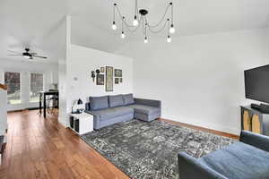 Living area featuring wood finished floors, a chandelier, ceiling fan, and lofted ceiling