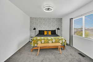 Carpeted bedroom with an accent wall and baseboards