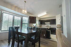 Dining area featuring a chandelier, light wood finished floors, and lofted ceiling
