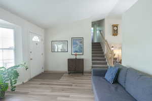 Entrance foyer featuring stairs, light wood-style flooring, and lofted ceiling