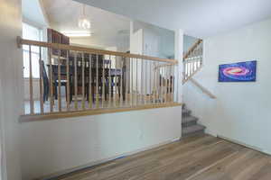 Stairs featuring wood finished floors and a chandelier