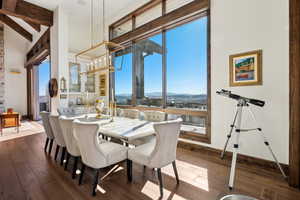 Dining room with plenty of natural light, dark wood-style floors, a mountain view, beamed ceiling, and a high ceiling