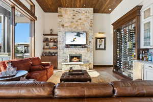 Living area featuring wood finished floors, wooden ceiling, a fireplace, and a bar