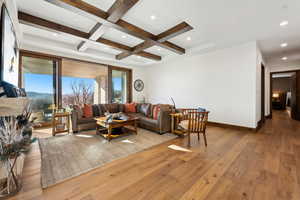 Living room featuring wood-type flooring, beam ceiling, coffered ceiling, and recessed lighting