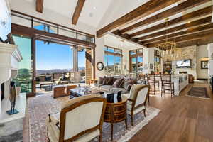 Living area featuring beamed ceiling, dark wood-style floors, a mountain view, a chandelier, and a towering ceiling