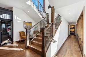 Stairs with hardwood / wood-style flooring, a towering ceiling, and recessed lighting