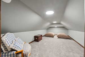 Sitting room with vaulted ceiling and carpet