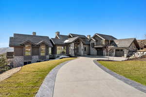 View of front of house featuring stone siding, curved driveway, and a front lawn