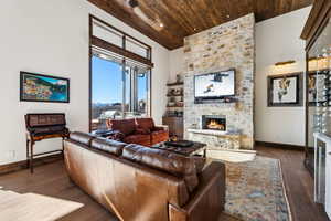 Living room featuring a fireplace, wooden ceiling, dark wood-style flooring, and high vaulted ceiling