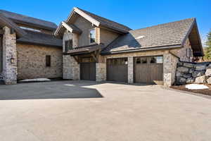 View of home's exterior with stone siding, driveway, and an attached garage
