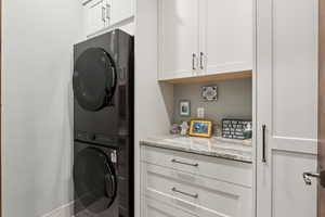 Washroom with stacked washer and clothes dryer and cabinet space
