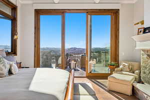 Bedroom featuring a mountain view, wood finished floors, access to exterior, crown molding, and a fireplace
