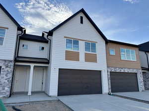 Multi unit property featuring stone siding, a garage, and driveway