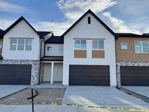 Multi unit property featuring stone siding, an attached garage, and driveway