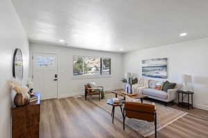 Living area with wood finished floors, healthy amount of natural light, recessed lighting, and a textured ceiling