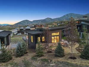 Back of property at dusk featuring a mountain view, a chimney, and a balcony