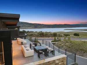 Balcony at dusk with a patio area, an outdoor living space, and a water and mountain view