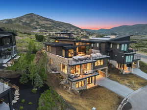Rear view of property with a balcony, stone siding, a chimney, a mountain view, and a patio