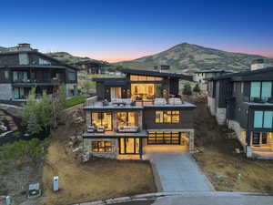 View of front of home featuring a balcony, driveway, stone siding, a mountain view, and an attached garage