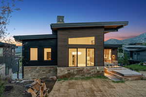 Back of property at dusk with stone siding
