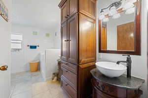 Bathroom with vanity, a textured ceiling, and tile patterned floors