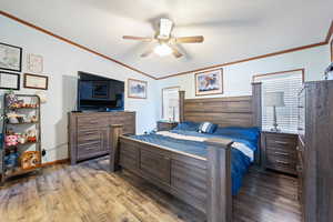 Bedroom featuring wood finished floors, a textured ceiling, ornamental molding, lofted ceiling, and a ceiling fan