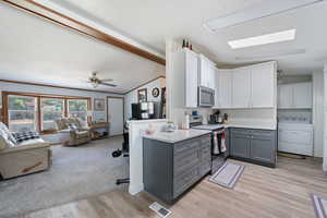Kitchen featuring washer / dryer, gray cabinetry, stainless steel appliances, open floor plan, and white cabinets