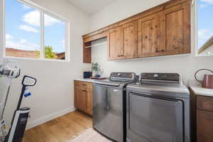 Laundry room featuring cabinet space, light wood-style floors, and washing machine and clothes dryer