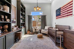 Bedroom featuring a chandelier, light wood finished floors, a crib, recessed lighting, and a high ceiling