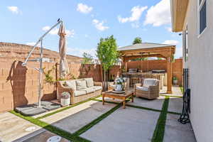 Fenced backyard with an outdoor hangout area, a patio area, a gazebo, and an outdoor kitchen