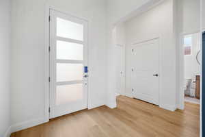 Foyer entrance with light wood finished floors and baseboards