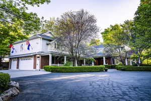 View of front of house featuring brick siding, a garage, covered porch, and asphalt driveway