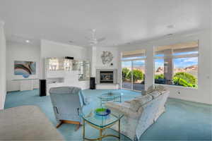 Living room featuring carpet floors, crown molding, a glass covered fireplace, ceiling fan, and recessed lighting