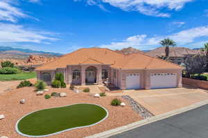 Mediterranean / spanish home with an attached garage, driveway, a tiled roof, stucco siding, and a mountain view