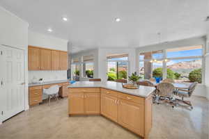 Kitchen with a kitchen island, recessed lighting, light countertops, built in study area, and a chandelier