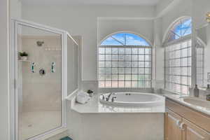 Full bathroom with healthy amount of natural light, a stall shower, vanity, and a bath