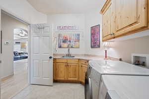 Laundry room featuring cabinet space, separate washer and dryer, ceiling fan, light tile patterned flooring, and bar with sink