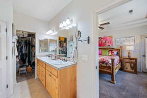 Bathroom featuring double vanity, a spacious closet, a ceiling fan, and tile patterned floors